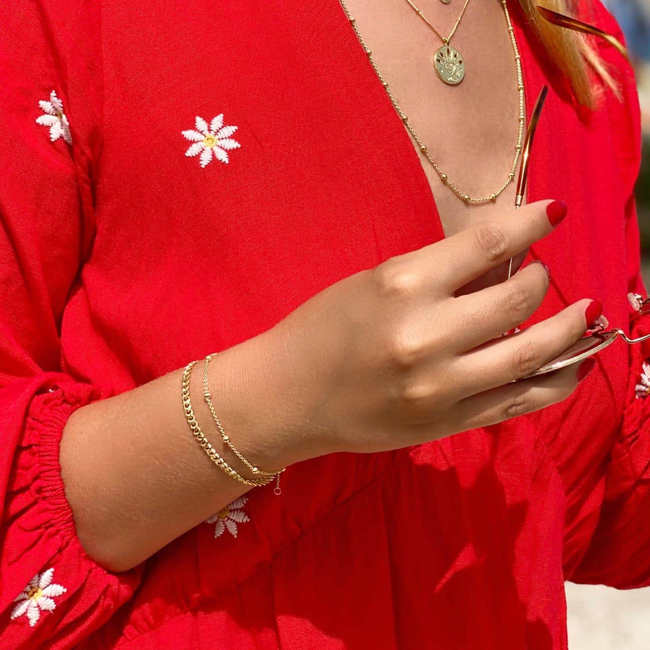 Model mit goldenen Armbänder und Halsketten im roten Sommerkleid in Lausanne